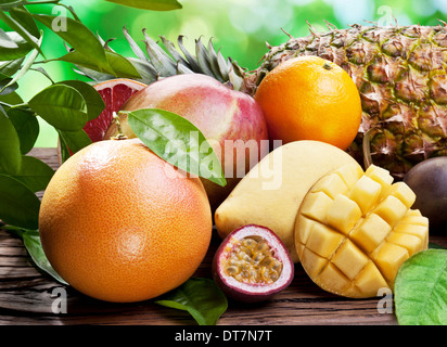 Exotic fruits on a wooden table with green foliage on the background. Stockfoto