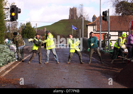 Burrowbridge, Somerset Levels, UK 11. Februar 2014. Bewohner und freiwillige Helfer weiter zu füllen und zu stapeln Sandsäcke an Burrowbridge in Bereitschaft. Graben Sie prahlen im Hintergrund. Stockfoto