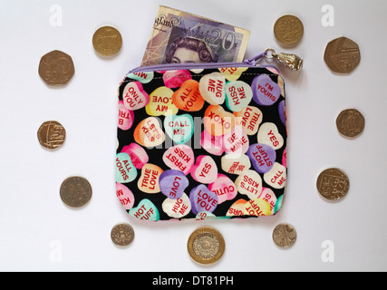 Liebe Herz Handtasche mit 20 Pfund-Note und britischen Münzen in der Form eines Herzens isoliert auf weißem Hintergrund Stockfoto