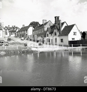 Historisches Bild von der 1950er Jahre zeigen eine Reihe von Hütten auf einem Hügel über einem Dorfteich, England. Stockfoto