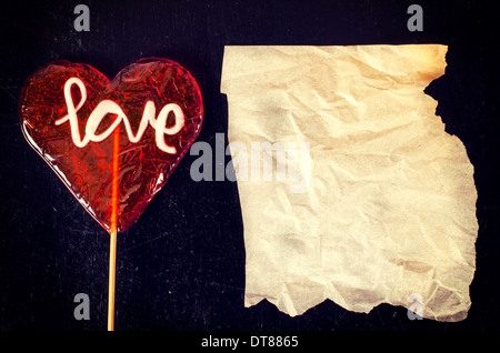 Herz-Form-Lolly pops auf dem hölzernen Hintergrund mit faltigen Blankopapier Stockfoto