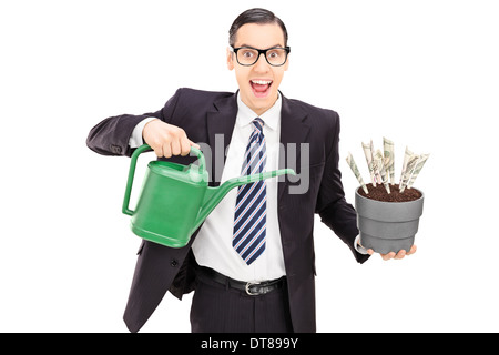 Junger Geschäftsmann mit Gießkanne und Blumentopf mit US-Dollar in es Stockfoto