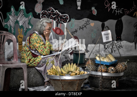 Thailändischer Straßenhändler. Ältere Frau, die auf dem Bürgersteig Obst verkauft. Thailand S. E. Asien Stockfoto