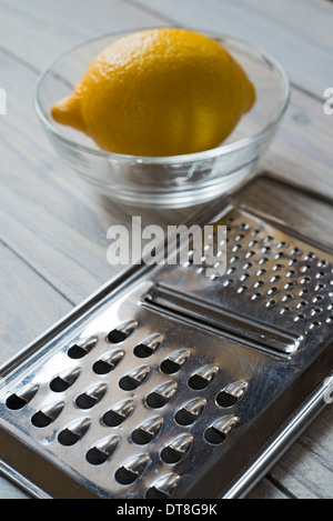 Zitrone, Schale und reibe auf einem Holzbrett. Tiefenschärfe über Reibe Stockfoto