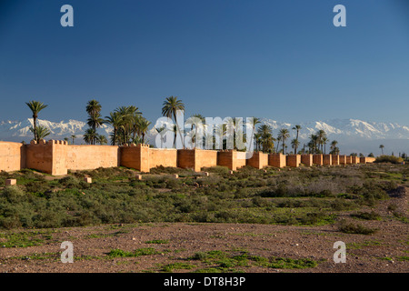 Rote Wände von Marrakesch mit schneebedeckten Berge und Palmen. Stockfoto