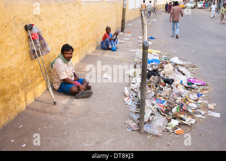 Armen behinderten Mann betteln auf eine indische Straße vor Müll. Andhra Pradesh, Indien Stockfoto