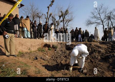 Peshawar, Pakistan. 12. Februar 2014. Ein pakistanischer Sicherheitsbeamter inspiziert die Website eines Angriffs durch militante in Nordwest-Pakistan Peshawar am 12. Februar 2014. Mindestens 10 Personen wurden getötet, als einige unbekannte Kämpfer das Haus eines lokalen Frieden Miliz Kommandanten in Pakistans nordwestlichen Peshawar City stürmten berichteten lokale Medien am Mittwoch Morgen. Bildnachweis: Umar Qayyum/Xinhua/Alamy Live-Nachrichten Stockfoto