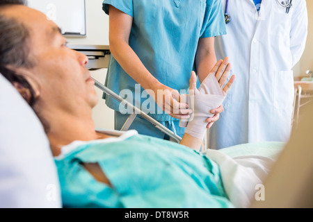 Krankenschwester Putt Verband an Hand des Patienten im Krankenhaus Stockfoto