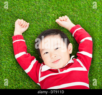 kleine lächelnde junge ruhen und Hand in Wiese oder Grünland Stockfoto