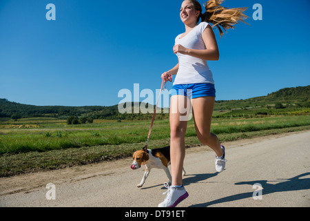 Schöne Teenager-Mädchen mit ihrem Haustier (Beagle-Hund) in der Natur joggen Stockfoto