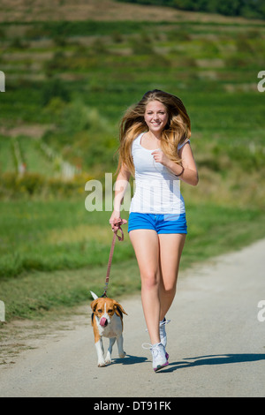 Schöne Teenager-Mädchen mit ihrem Haustier (Beagle-Hund) in der Natur joggen Stockfoto