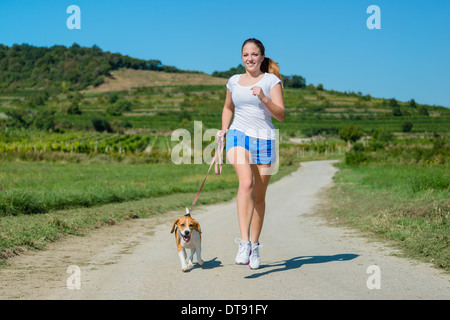 Schöne Teenager-Mädchen mit ihrem Haustier (Beagle-Hund) in der Natur joggen Stockfoto