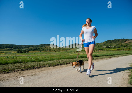 Schöne Teenager-Mädchen mit ihrem Haustier (Beagle-Hund) in der Natur joggen Stockfoto