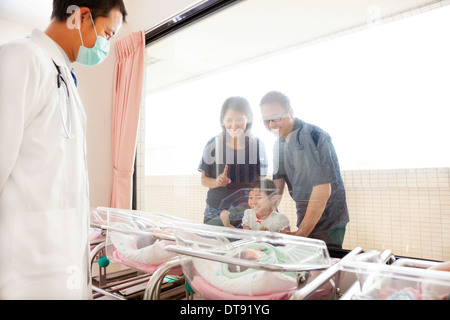 Familie vor dem Neugeborenen bei gebärfähigen Zentrum und Arzt Stockfoto
