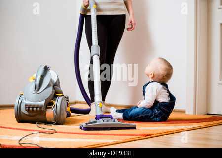 Aufräumen der Zimmer - Frau mit Staubsauger, Baby-sitting auf Etage Stockfoto