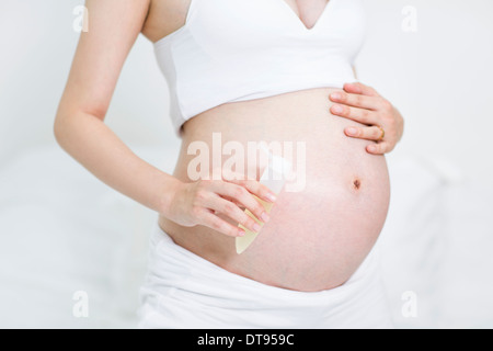 Schwangere Frau mit lotion Stockfoto