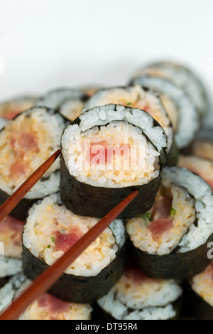 Closeup vertikale Foto von einem einzigen würzige Thunfisch Rollen auf Sushi Stapel mit Stäbchen abgeholt Stockfoto