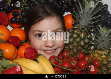 Kaukasische Mädchen Gesicht umgeben von Obst und Gemüse, fünf eine Tag, England, UK Stockfoto