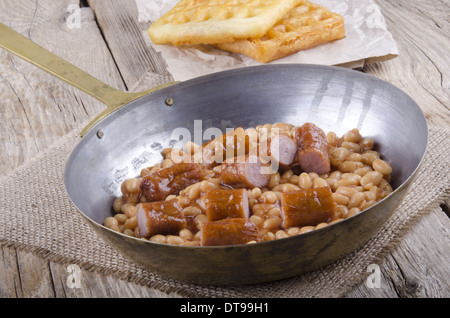 gebackene Bohnen mit Bratwurst und nach Hause gemachte Waffeln in einer Pfanne Stockfoto