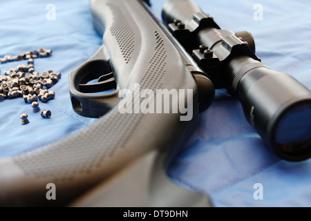 Teil von einem Luftgewehr und einige Pellets auf blauem Hintergrund Stockfoto