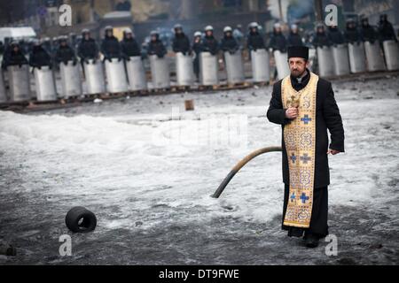 Kiew, Ukraine. 12. Februar 2014. Ein Priester betet zwischen Polizei und Demonstranten in der Szene der Anti-Regierungs-Proteste in der Nähe von Dynamo-Stadion am 12. Februar 2014 in Kiew, Ukraine. Gewaltsame Proteste in der Ukraine haben jenseits der Hauptstadt verbreitet, wie Präsident Viktor Yanukovych Krise mit drei wichtige Oppositionsführer Gespräche. Foto von Emeric Fohlen/NurPhoto Credit: Emeric Fohlen/NurPhoto/ZUMAPRESS.com/Alamy Live-Nachrichten Stockfoto