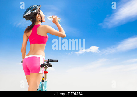 Junge Frau Trinkwasser mit Faltrad mit sonnigen Tag Stockfoto