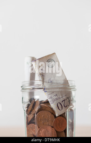 Glas mit Pfund-Banknoten und Münzen Stockfoto