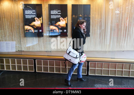 Berlin, Deutschland. 12. Februar 2014. Eine Frau erzählt über ihr Handy vor Filmplakate im Zoo Palast Kino in Berlin, Deutschland am 12. Februar 2014. Bekannt als "Berlinale Heimat", wurde der Berliner Zoo Palast Kino Berlinale Hauptschauplatz von 1957 bis 1999. Nach umfangreichen Sanierungsarbeiten seit Ende 2010 das Kino wurde am 27. November 2013 wieder eröffnet und wurde wieder ein wichtiger Standort für die 64. Internationalen Filmfestspiele Berlinale im Jahr 2014. © Zhang Fan/Xinhua/Alamy Live-Nachrichten Stockfoto