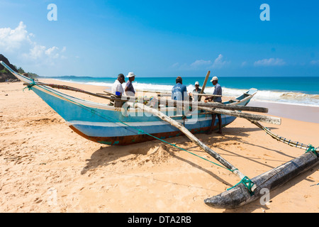 Traditionelle Fischer mit einem Ausleger Boot am Strand, in der Nähe von Duwemodara Galle Region südliche Provinz, Sri Lanka Stockfoto