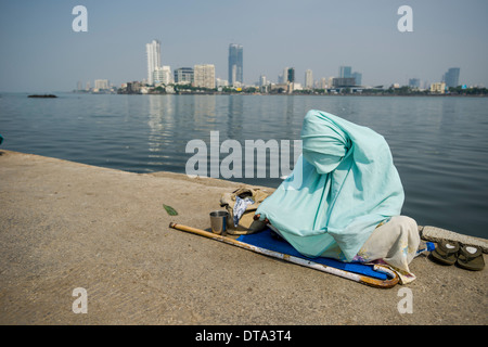 Eine muslimische Frau, die eine Burka tragen ist betteln um Geld auf dem Gehweg, Mahalaksmi, Mumbai, Maharashtra, Indien Stockfoto