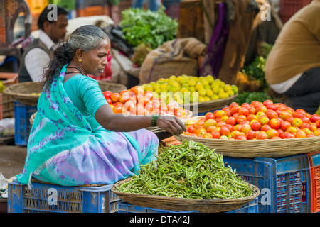 Eine Frau verkauft Chilis und Tomaten auf dem Wochenmarkt Gemüse Nasik, Maharashtra, Indien Stockfoto