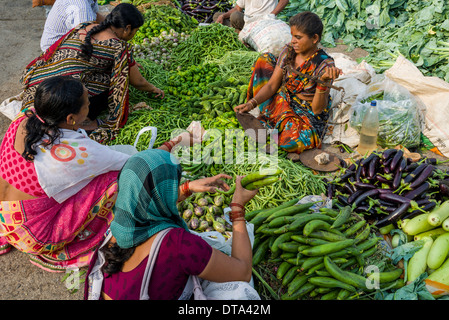 Eine Frau verkauft Auberginen, Paprika, Blumenkohl und Gurken auf dem Wochenmarkt Gemüse Nasik, Maharashtra, Indien Stockfoto