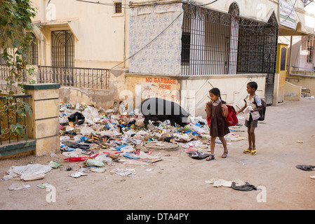 Indische Schulkinder vorbei an Müll geworfen in eine "Bygata". Andhra Pradesh, Indien Stockfoto