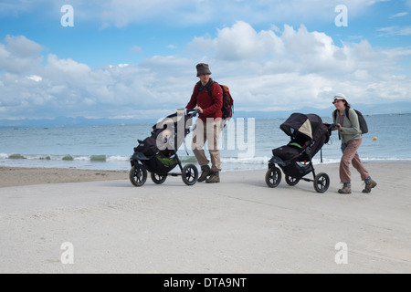 Ein paar nehmen ihre Babys für ein Septembermorgen Spaziergang am Strand in Abersoch, North Wales Stockfoto