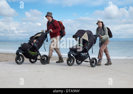 Ein paar nehmen ihre Babys für ein Septembermorgen Spaziergang am Strand in Abersoch, North Wales Stockfoto