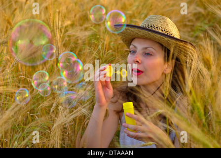 Mädchen im Weizenfeld im weißen Kleid und Stetson Hut Seifenblasen. Selektiven Fokus. Stockfoto
