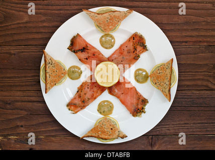 Geräucherter Lachs Vorspeise, angeordnet auf einer Platte mit einem Table-Top-Hintergrund Stockfoto