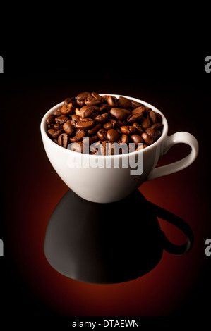 Dunkle Röstung Espresso Kaffeebohnen in kleine Espressotasse auf reflektierenden Hintergrund Stockfoto