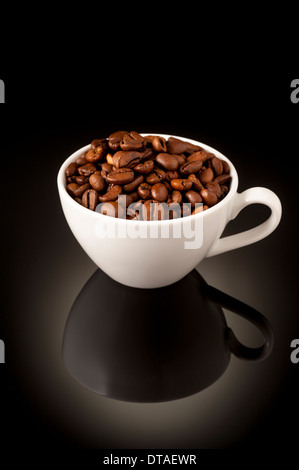 Dunkle Röstung Espresso Kaffeebohnen in kleine Espressotasse auf reflektierenden Hintergrund Stockfoto