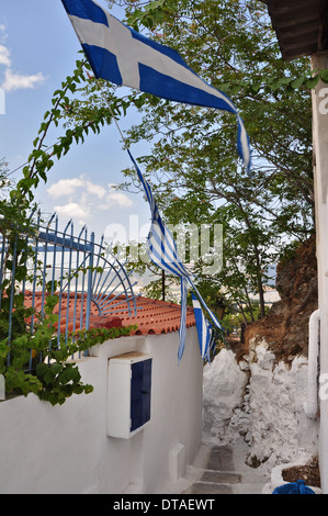 Schmale Gasse mit griechischen Fahnen und kleines Haus im traditionellen Anafiotika Stadtteil, Athen, Griechenland. Stockfoto