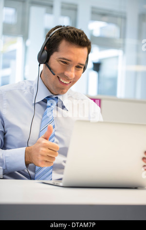 Geschäftsmann im Büro am Telefon mit Kopfhörer, Skype Stockfoto