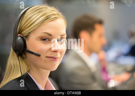 Porträt der Geschäftsfrau im Büro am Telefon mit Kopfhörer, Kamera suchen Stockfoto