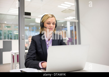 Geschäftsfrau im Büro am Telefon mit Kopfhörer, video-Konferenz Stockfoto