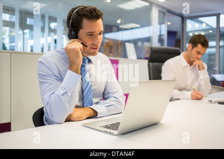 Kaufmann im Büro am Telefon mit Kopfhörer, Konferenzgespräch Stockfoto
