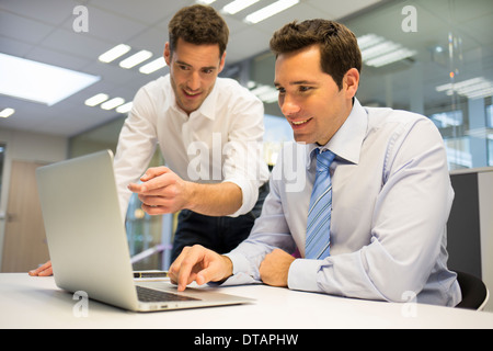 Zwei hübsche Geschäftsmann arbeiten gemeinsam an einem Laptop im Büro Stockfoto