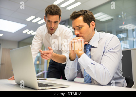 Zwei hübsche Geschäftsleute arbeiten gemeinsam an einem Laptop im Büro Stockfoto