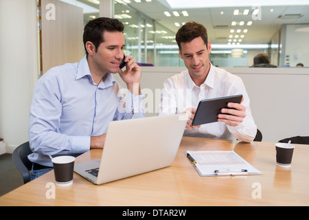 Zwei lässige Geschäftsleute arbeiten zusammen im Büro mit Laptop und Tablet pc Stockfoto