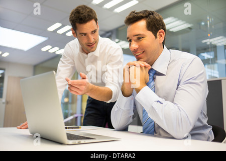 Zwei hübsche Geschäftsleute arbeiten gemeinsam an einem Laptop im Büro Stockfoto