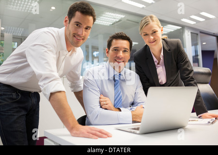 Ein Team von drei amtierenden lächelnd und Planungsarbeiten, aussehende Kamera Stockfoto