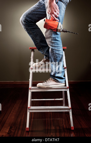 Mann mit Bohrer auf Leiter arbeitet Stockfoto